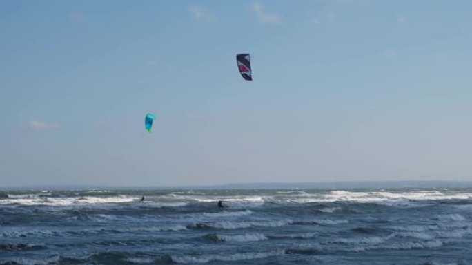 一名穿着潜水服、带着降落伞的男子在海浪上冲浪。一个年轻人顶着天空在空中表演魔术。水上运动，风筝冲浪，