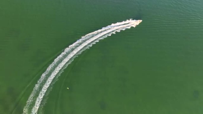 白色快艇在波浪表面快速游动的鸟瞰图。机动船在海洋上高速行驶