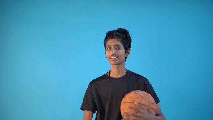一个有趣的年轻印度男孩穿着黑色t恤嬉戏地转动球