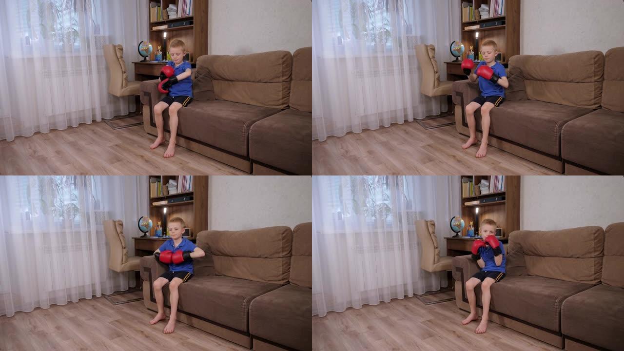 一个小男孩在家里的沙发上戴上拳击手套。