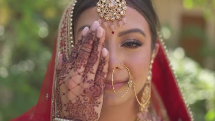 一位幸福的印度新娘用手遮住脸的肖像，手在印地语上