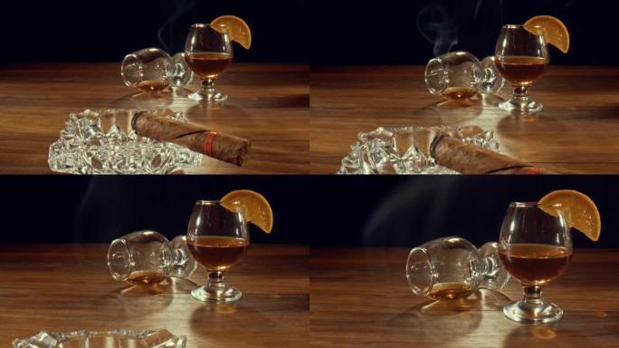 烟灰缸，配有点燃的雪茄，被推翻的玻璃杯以及一杯威士忌和橙子