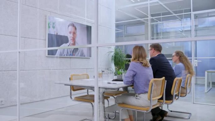 DS人坐在会议室里，与商人进行视频会议