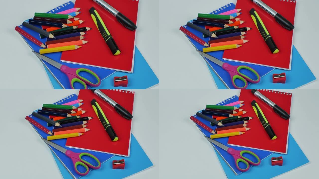 浅色背景上的文具，一套用于绘画的彩色铅笔，两个记号笔，卷笔刀，剪刀，记事本和彩纸。儿童创意办公用品的