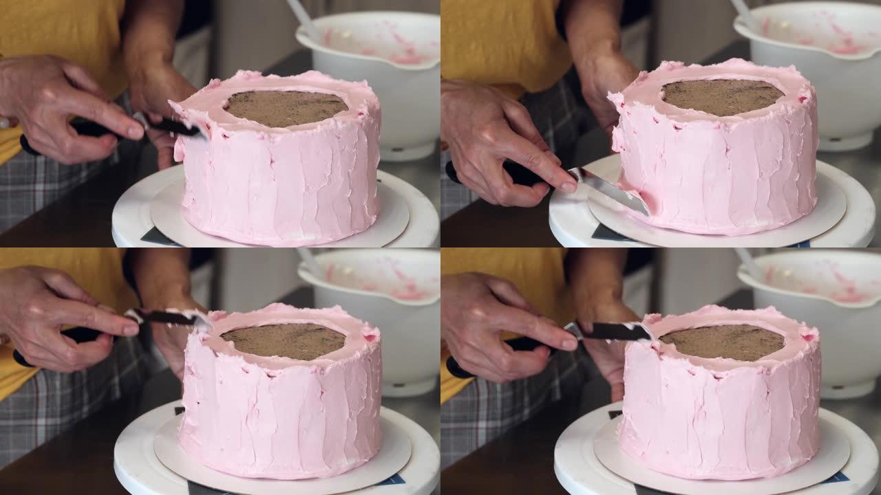 女人用粉红色奶油芝士装饰巧克力蛋糕特写。慢动作。蛋糕制作过程