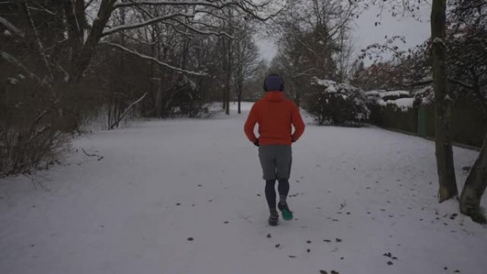 冬天在湿滑的表面上跑的衣服和鞋子不对。男子在雪地寒冷的天气慢跑和滑倒。滑溜溜的运动鞋，鞋底错误，可在