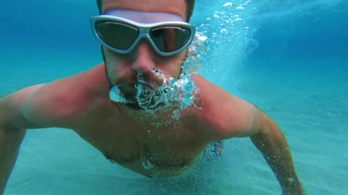 男子在水面下潜水。向相机游泳