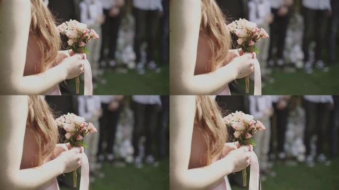 年轻的女人拿着一束玫瑰和满天星，上面系着丝带。