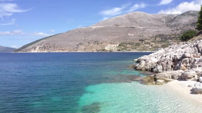 缓慢飞行的无人机在Cephalonia希腊岛岩石海岸白色卵石舒适的海滩。离子海浪景观4k镜头。大自然