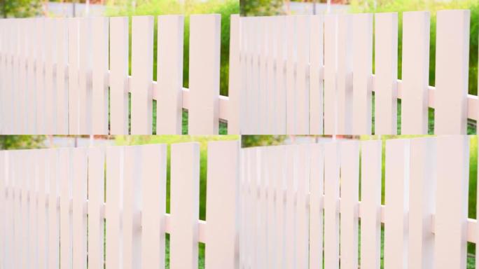 在阳光明媚的夏季天气里，摄像机沿着一个模糊背景的白色木栅栏平滑移动。自制的整洁时尚的街道围栏