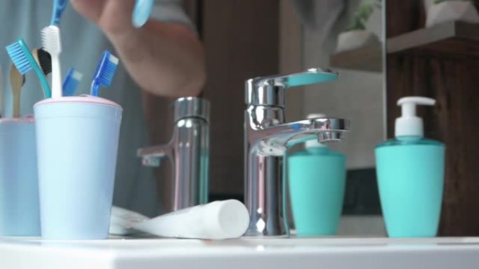 一名男子在浴室镜子前扔掉旧牙刷。牙科保健。健康牙齿概念。男人在浴室刷牙。更换旧牙刷