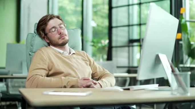 精疲力竭的年轻办公室工作人员戴着眼镜在工作场所打do睡