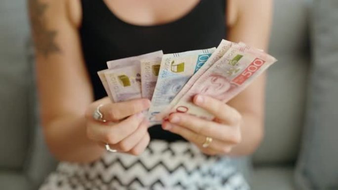 年轻女子在家中数数瑞典克朗的钞票