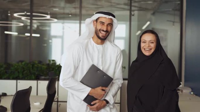 英俊的男人和女人穿着传统的衣服在迪拜的办公室工作
