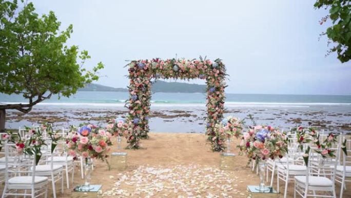 风景婚礼装饰金色椅子白布粉色鲜花仪式在海滩上。豪华目的地婚礼背景。