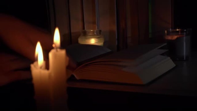 女人的手在烛光下翻阅旧书