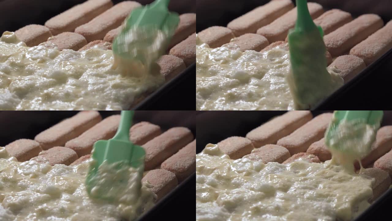 准备提拉米苏蛋糕，在预先制作的饼干上涂上奶油。特写。