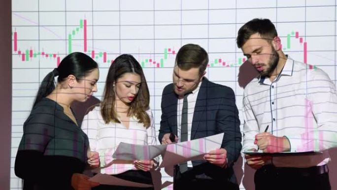 一组商人在办公室开会，以股票市场图表为背景。商业和技术概念。金融科技。金融科技