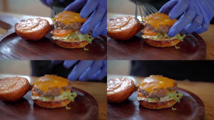 戴着蓝手套的厨师把多汁的炸肉和芝士肉饼放进汉堡里