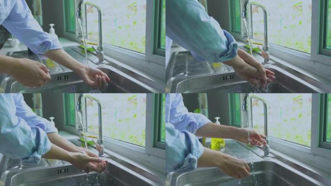 穿着蓝色衬衫的女人洗手。吃饭前，在厨房水槽里用水和泡沫肥皂清洁手指。概念细菌安全