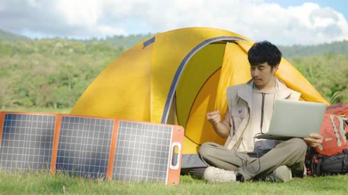 4K，年轻的旅行家放松，享受露营。便携式太阳能电池板用多功能电缆为笔记本电脑充电，清洁能源，用于野营