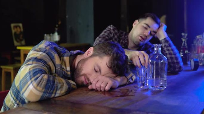 两个非常醉酒的男人在酒吧酒吧里，其中一个睡在桌子上