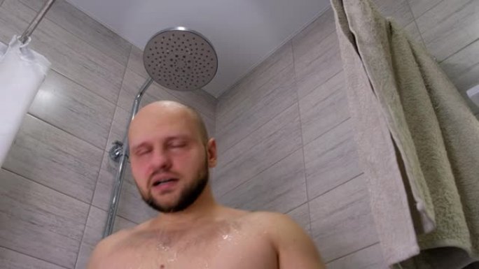 沟通问题。一个留着胡须的肌肉发达的秃头男人在淋浴下的浴室里洗，关掉水，用毛巾擦拭身体