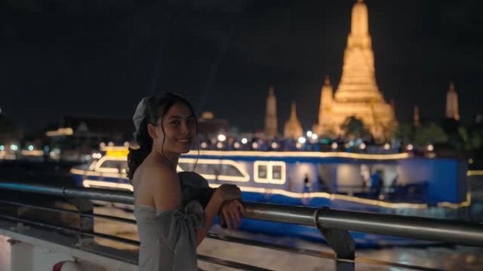 夜间在曼谷湄南河巡游期间，亚洲妇女与Wat Arun或黎明神庙一起观光