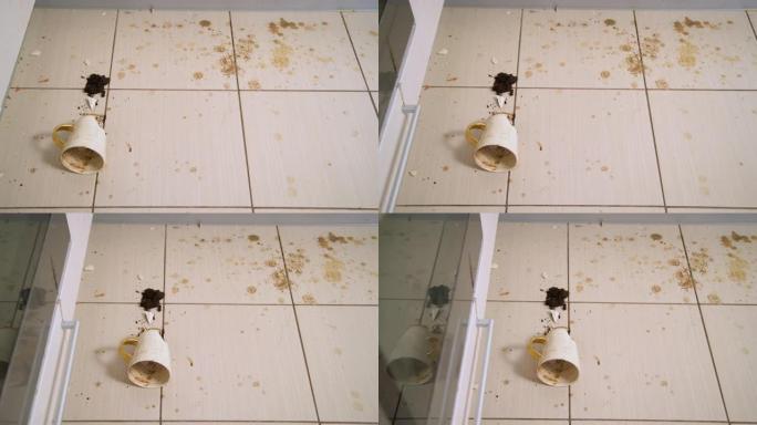 破碎的茶杯躺在厨房地板上，砸碎的咖啡杯和咖啡渣遍布瓷砖。