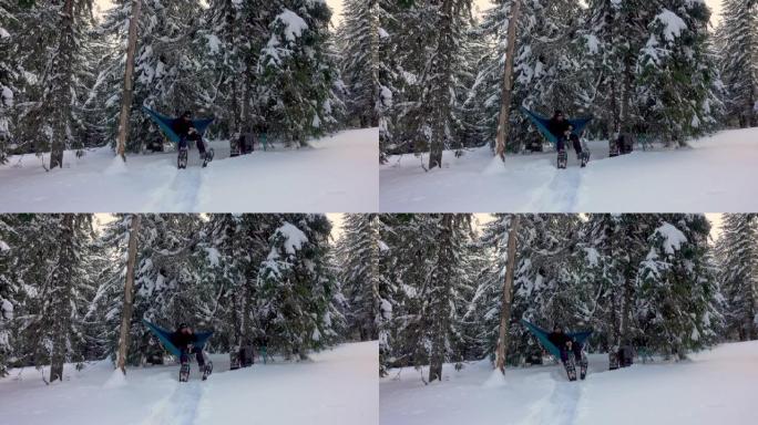 徒步旅行者带着雪鞋喝咖啡，躺在冬季森林的吊床上