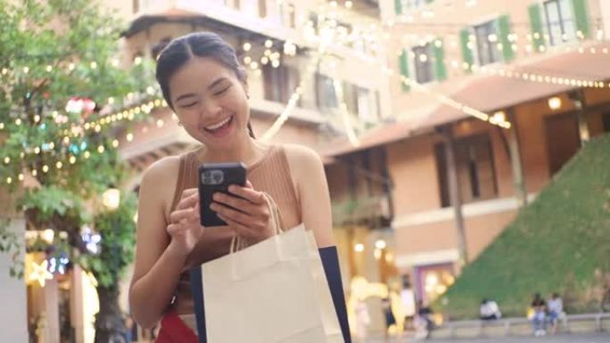 快乐的亚洲女人，她用纸袋购物。保持清洁和减少全球变暖