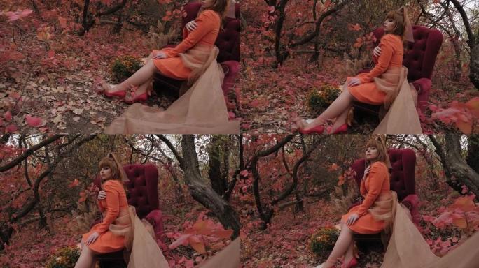 秋天，一个模特在树林里摆姿势，旁边是红色的古董椅子和南瓜。