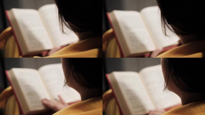 女人在看书。女人的俯视图在晚上看书，翻页。特写镜头