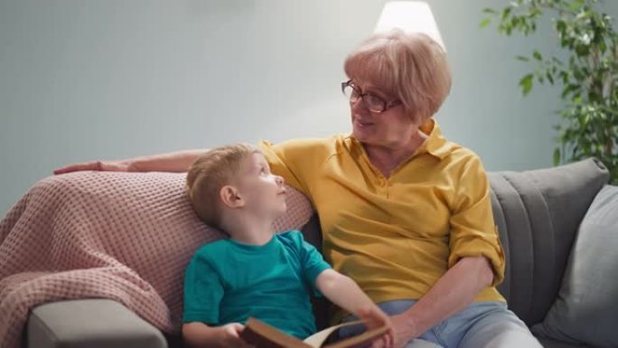有趣的小男孩在客厅里和奶奶翻书