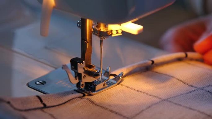 在缝纫机上的缝纫过程中，用一根线和一个固定器将白色方格织物缝合。