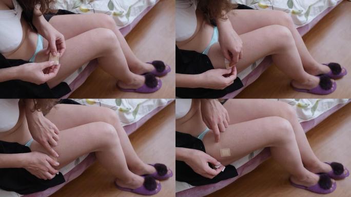 该妇女在大腿上部的皮肤上涂抹了一个HRT贴片。