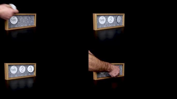 一个木制日历块，用男人的手2月23日和取下带有日期和月份的金属盘，以4k质量拍摄