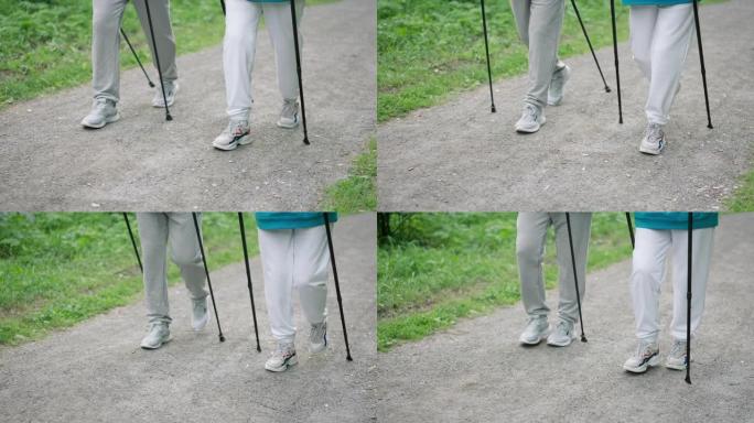 脚踩特写。人们的腿与北欧杆木公园同行。徒步旅行棒