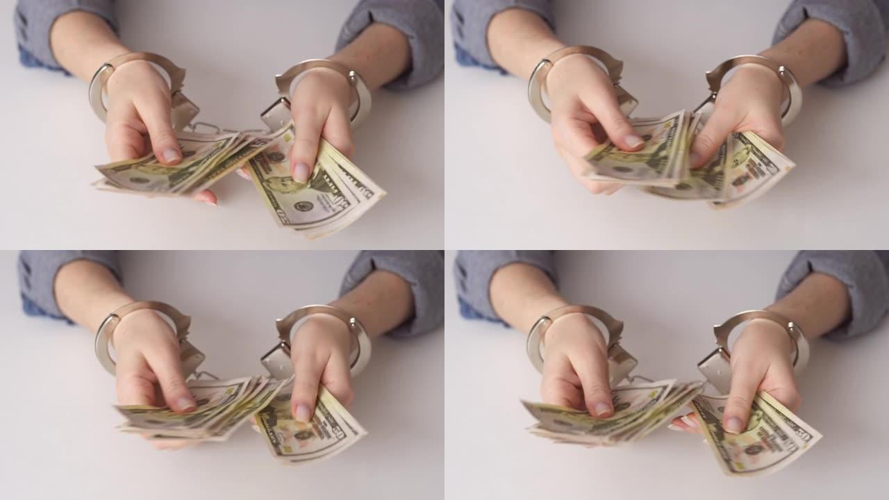 女人的手戴着手铐，数着手里的美元。