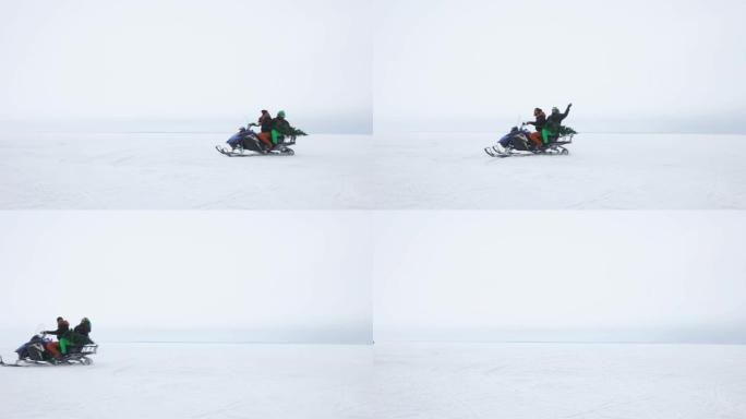 年轻的家庭带着圣诞树雪地摩托穿越雪原，假期