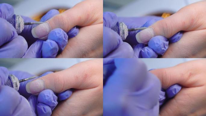 戴着蓝色手套的修指甲大师的手使用电动指甲锉去除角质层