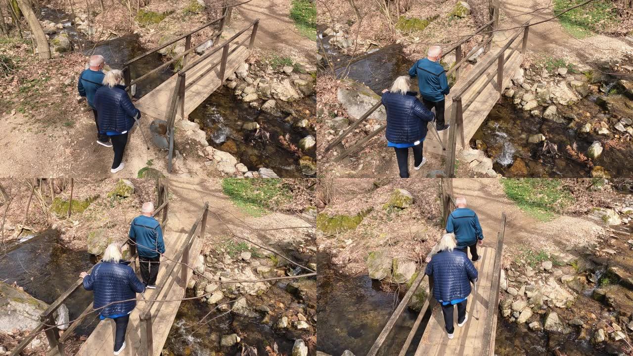 老年夫妇在creek木桥上的森林中徒步旅行，慢动作