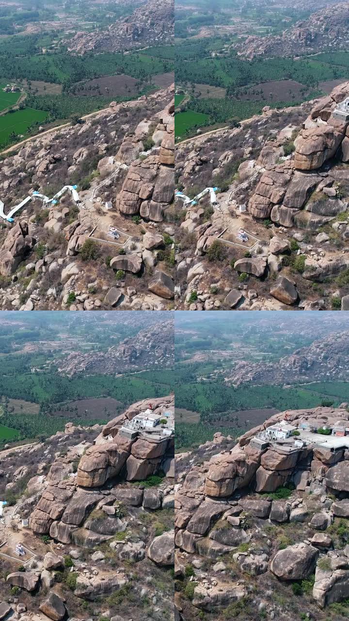岩石巨石山空中拍摄的垂直视频，顶部是白色神庙，底部是田野