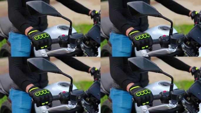 一只手被一个匿名男子的驾驶手套遮盖的特写镜头，他坐在摩托车上移动加速器手柄