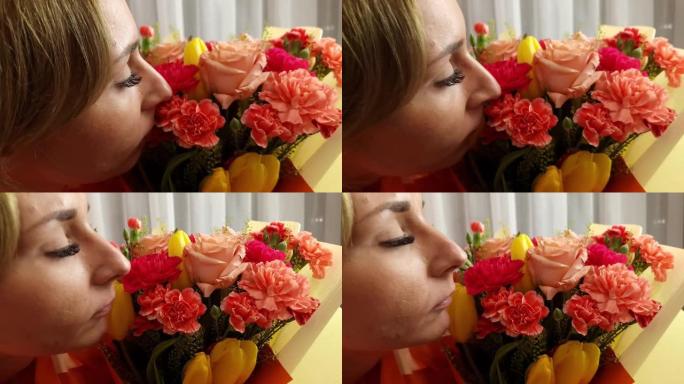 妇女节。女人闻到一束玫瑰，郁金香和康乃馨的花朵