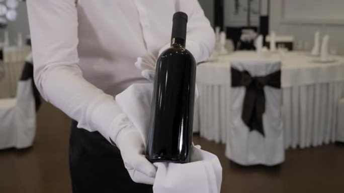 一个服务员在餐厅拿着一瓶酒的特写镜头。