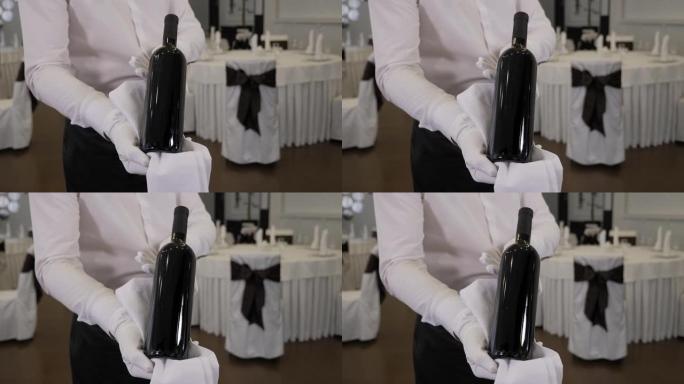 一个服务员在餐厅拿着一瓶酒的特写镜头。