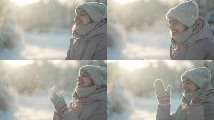 慢动作: 年轻女子吹雪。寒冷的冬日降雪后，有趣的女孩在冬季公园的手套上吹雪。快乐兴奋的女孩享受寒冷的