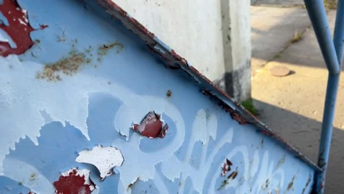 墙壁旁边的旧金属楼梯，蓝色油漆碎裂