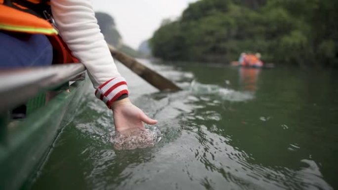 亚洲华裔女孩的手触碰河面